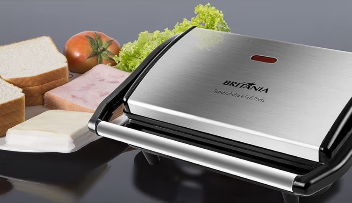 Sanduicheira e Grill Britânia BGR27I em inox sobre a mesa com pão, presunto, queijo, tomate e alface